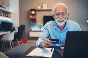 Mature Male Smiling at Camera with Credit Card in Hand